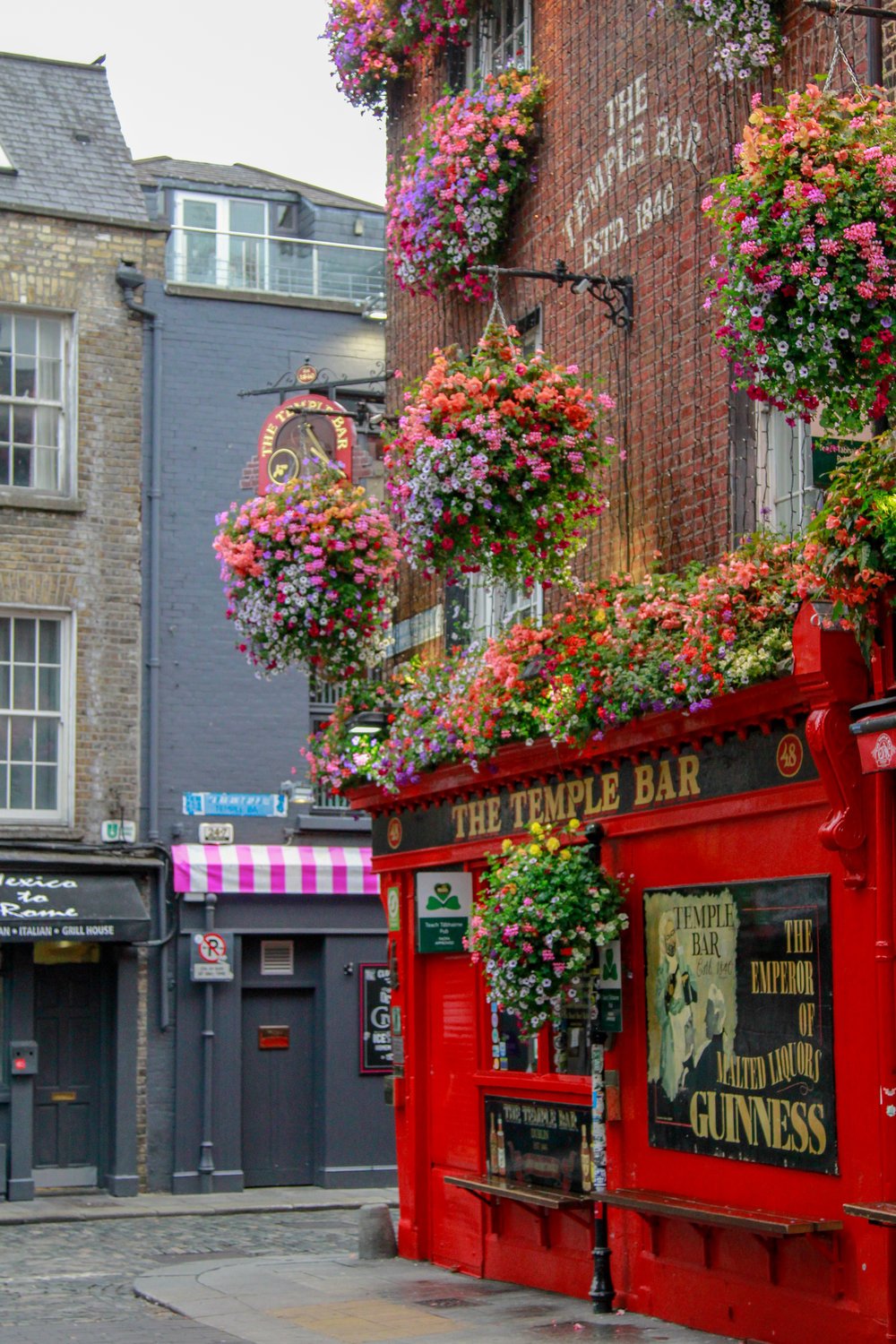 Temple Bar in Dublin, Ireland, a famous pub with vibrant red walls and hanging flower baskets in the city's cultural district.