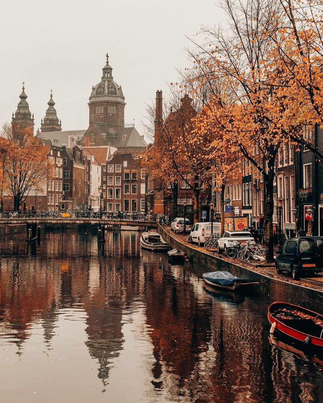 Destination Autumn in Amsterdam – Scenic canal view with historic buildings and St. Nicholas Basilica.
