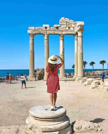 Tourist admiring the ancient Temple of Apollo ruins by the sea in Antalya, Turkey.