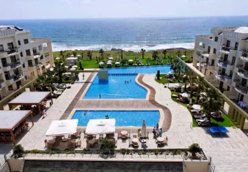 Pool area and outdoor facilities at Capital Coast Resort & Spa in Paphos, Cyprus, overlooking the sea