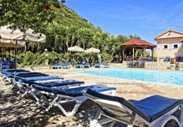 Swimming pool area surrounded by lush greenery at Nostos Hotel in Ithaca, Greece